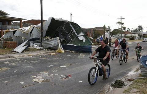 Residents from Sydney's southern suburb of Kurnell assess the damage from a houses's roof which had blown down the street following a rare tornado, December 16, 2015. PHOTO BY REUTERS/Jason Reed