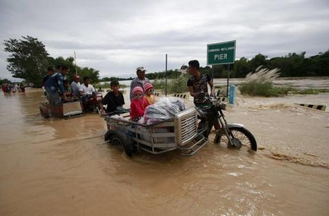 Residents ride on motorcycle taxi to cross a flooded road after heavy rain at Candaba town, Pampanga province, north of Manila, December 17, 2015. PHOTO BY REUTERS/Romeo Ranoco