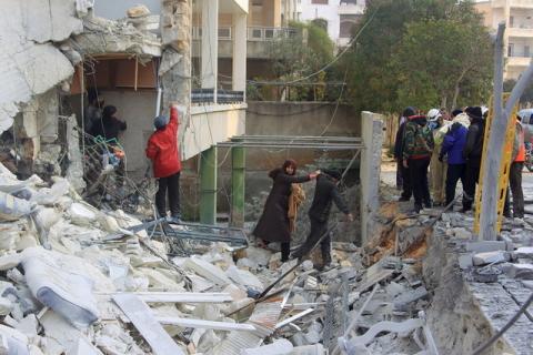 A man helps a woman making her way through the rubble of a damaged building after what activists said were airstrikes carried out by the Russian air force in Idlib city, Syria, December 20, 2015. PHOTO BY REUTERS/Ammar Abdullah