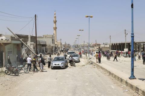 Residents inspect a site hit by what activists say was a barrel bomb dropped by forces loyal to Syria's President Bashar al-Assad in Saida village in the eastern countryside of Deraa