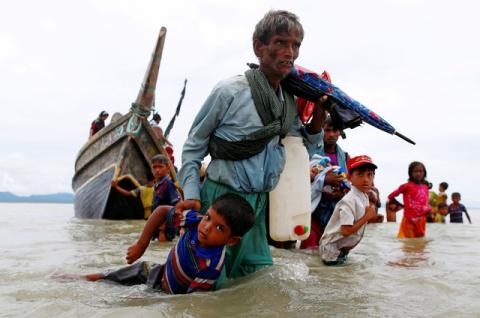 A Rohingya refugee man pulls a child as they walk to the shore after crossing the Bangladesh-Myanmar border by boat through the Bay of Bengal in Shah Porir Dwip, Bangladesh, September 10, 2017. PHOTO BY REUTERS/Danish Siddiqui