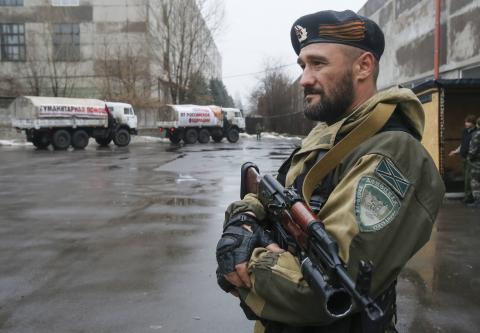 A pro-Russian-separatist patrols the street in front of Russian humanitarian trucks in Makiivka (Makeyevka) in Donetsk region, December 12, 2014. PHOTO BY REUTERS/Maxim Shemetov