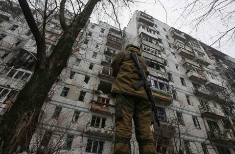 A pro-Russian separatist stands guard in front of a building damaged during fighting between pro-Russian rebels and Ukrainian government forces near Donetsk Sergey Prokofiev International Airport, eastern Ukraine, December 16, 2014. PHOTO BY REUTERS/Maxim Shemetov