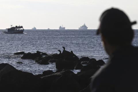 A container ship (C) is being towed by a Greek Navy frigate (2nd R) as a coast guard officer looks on, at open sea a few miles southeast from the island of Crete, November 27, 2014. PHOTO BY REUTERS/Stefanos Rapanis