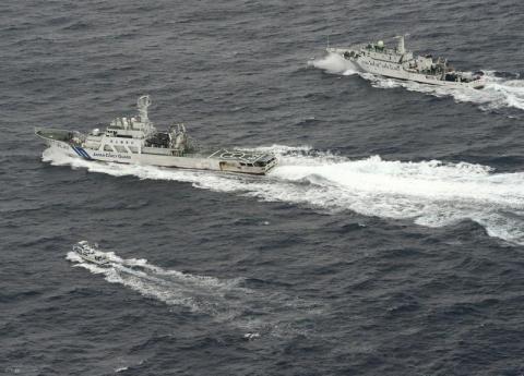 An aerial photo shows Chinese marine surveillance ship Haijian No. 66 (top) trying to approach a Japanese fishing boat (bottom) as Japan Coast Guard vessel Ishigaki cruises next to the Chinese ship, in the East China Sea, near what are known as the Senkaku isles in Japan and the Diaoyu islands in China