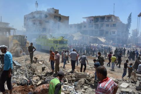 Smoke rises while people gather at a damaged site after two bomb blasts claimed by Islamic State hit the northeastern Syrian city of Qamishli near the Turkish border, Syria, July 27, 2016. PHOTO BY REUTERS/Rodi Said