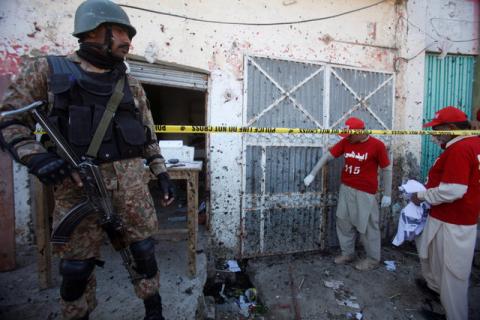 A soldier stands guard as voluteers collect remains of the walls and doors around the site of a blast at the courthouse in Charsadda, Pakistan, February 21, 2017. PHOTO BY REUTERS/Fayaz Aziz