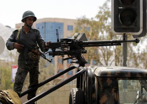 A soldier stands guard on a military vehicle at a checkpoint on a road to the city of Sanaa