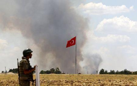 A Turkish soldier stands guard while smoke rises in the Syrian town of Kobani as it is seen from the Turkish border town of Suruc in Sanliurfa province, Turkey, June 26, 2015. PHOTO BY REUTERS/Murad Sezer