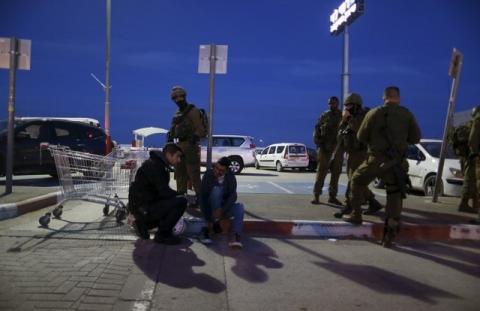 Israeli soldiers stand guard as a medic checks an Israeli man near the scene of a stabbing attack near the West Bank city of Ramallah, February 18, 2016. PHOTO BY REUTERS/Ammar Awad
