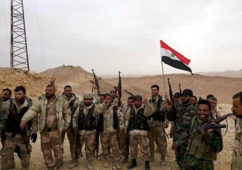Forces loyal to Syria's President Bashar al-Assad flash victory signs and carry a Syrian national flag on the edge of the historic city of Palmyra, March 26, 2016. PHOTO BY REUTERS/SANA