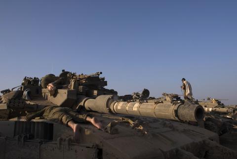 Israeli soldiers sleep atop a tank outside the Gaza Strip