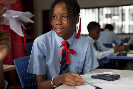 A student wears red ribbons to express solidarity with the abducted Nigerian schoolgirls from the remote area of Chibok, as she does maths exercise at the Regent Secondary School in Abuja, May 14, 2014. PHOTO BY REUTERS/Joe Penney