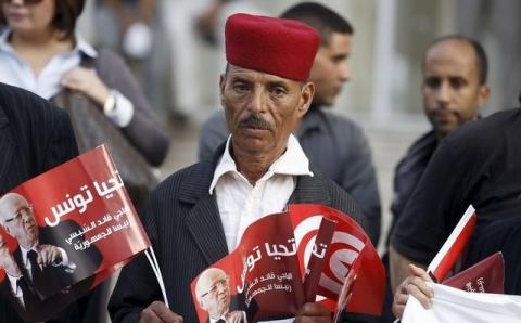 A supporter of the Nidaa Tounes party holds pictures of President Beji Caid Essebsi, in Tunis, Tunisia, November 3, 2015. PHOTO BY REUTERS/Zoubeir Souissi