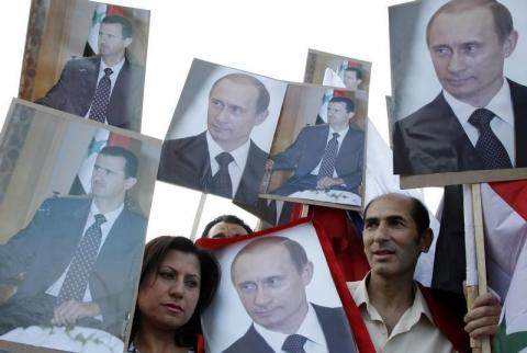 Supporters of Syrian President Bashar al-Assad holds signs with images of al-Assad and Russian President Vladimir Putin after Putin was sworn in as president on Monday, in front of the Russian embassy in Damascus, May 7, 2012. PHOTO BY REUTERS/Khaled al- Hariri