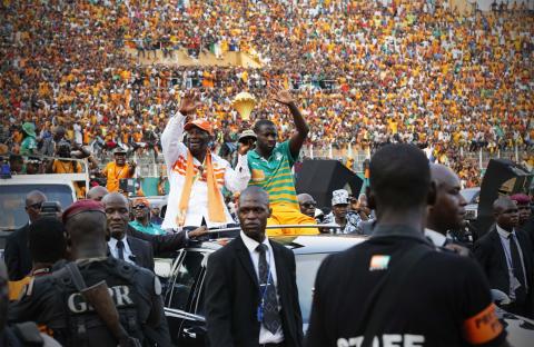 Ivory Coast's President Alassane Ouattara (centre L) waves as he holds the African Nations Cup trophy with Ivory Coast's soccer team captain Yaya Toure, at the Felix Houphouet-Boigny stadium in Abidjan February 9, 2015. PHOTO BY REUTERS/Thierry Gouegnon
