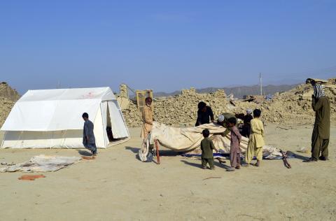Survivors of an earthquake prepare to fix makeshift tents for shelter near the rubble of a mud house after it collapsed following the quake at Dhallbedi Peernder village in Awaran district
