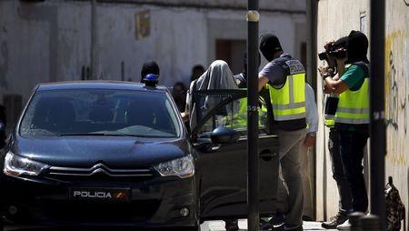 A suspect (L) is led by Spanish National Police officers after being arrested in San Martin de la Vega, near Madrid, Spain, August 25, 2015. PHOTO BY REUTERS/Sergio Perez