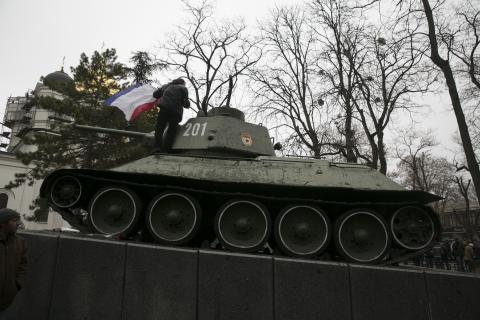 An ethnic Russian Ukrainian man holds the Crimea flag on top of an old Soviet tank during rallies near the Crimean parliament building in Simferopol