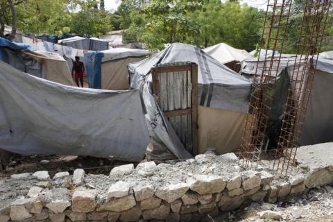 A woman made homeless by the 2010 earthquake, walks between tents as a wall (foreground) is being built by the owners of the land where she lives in Shelter Camp 3, one of 385 informal 'tent cities' still existing since the disaster, in the Delmas suburb of Port-au-Prince, April 22, 2013. PHOTO BY REUTERS/Marie Arago
