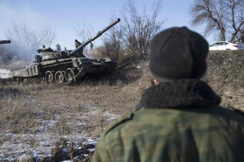 A man watches a tank of the separatist self-proclaimed Donetsk People's Republic Army manoeuvre near a checkpoint on the road from the town of Vuhlehirsk to Debaltseve, February 18, 2015. PHOTO BY REUTERS/Baz Ratner 