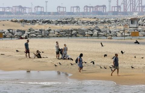 Tourists rest near the "Colombo Port City" construction site, backed by Chinese investment, in Colombo, February 8, 2016. PHOTO BY REUTERS/Dinuka Liyanawatte