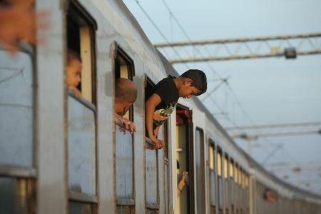 A young migrant hangs out from the window of a train while waiting to depart from the railway station in Tovarnik, Croatia, September 22, 2015. PHOTO BY REUTERS/Marko Djurica