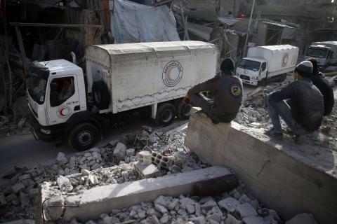 Civil defence members sit amid the rubble as they watch an aid convoy of Syrian Arab Red Crescent driving through the besieged town of Douma, Eastern Ghouta, Damascus, Syria, March 5, 2018. PHOTO BY REUTERS/Bassam Khabieh