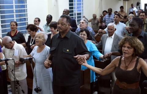 U.S. civil rights activist Jesse Jackson (C) holds hands with believers during a religious service