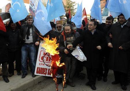Ethnic Uighur demonstrators, waving blue East Turkestan flags, set fire to a Chinese flag during a protest against China's Xi Jinping's visit in Ankara, February 21, 2012. PHOTO BY REUTERS/Stringer