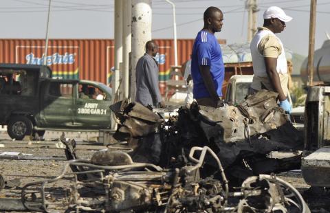 A military vehicle and people pass site of an explosion at a police station in Kano, November 15, 2014. PHOTO BY REUTERS/Stringer