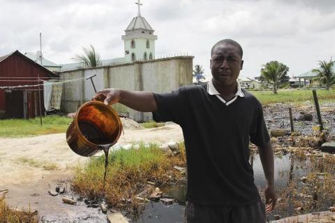 A villager shows a bucket of of crude oil spill at the banks of a river, after a Shell pipeline leaked, in the Oloma community in Nigeria's delta region, November 27, 2014. PHOTO BY REUTERS/Tife Owolabi