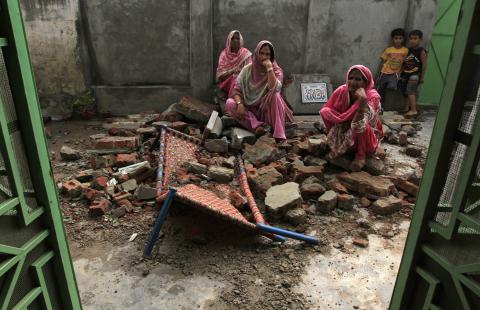 Villagers sit on the debris of their house after it was damaged during the recent exchange of fire between Pakistan and India at the Pakistani border town of Dhamala Hakimwala near Sialkot