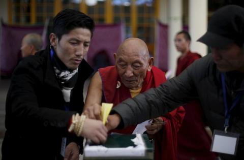 Polling officers help a Tibetan monk (C) to cast his vote during the election for the Tibetan government-in-exile at a polling booth in Dharamsala, India, March 20, 2016. PHOTO BY REUTERS/Adnan Abidi