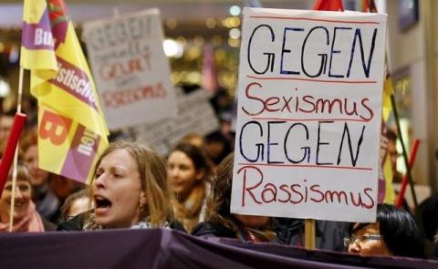 Women shout slogans and hold up a placard that reads "Against Sexism - Against Racism" as they march through the main railways station of Cologne, Germany, January 5, 2016. PHOTO BY REUTERS/Wolfgang Rattay