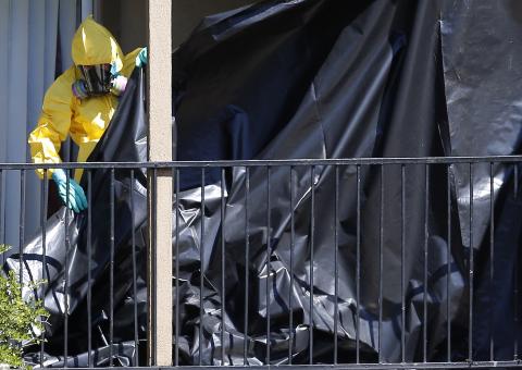 A worker wearing a hazardous material suit puts up a tarp at the apartment unit where Thomas Eric Duncan, a Liberian citizen diagnosed with the Ebola virus, was staying in Dallas, Texas