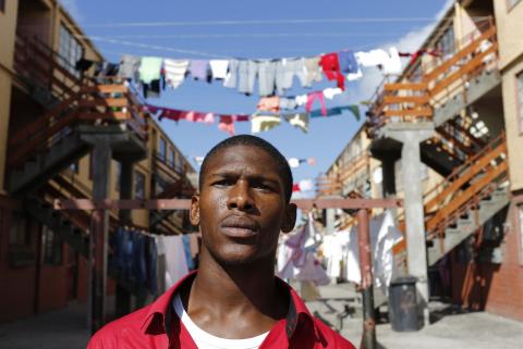 Youth worker Nathaniel Groep, 19, stands in front of flats outside his home in Mannenberg, a gang-ravaged township, in Cape Town