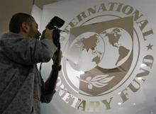 A photographer takes pictures through a glass carrying the International Monetary Fund (IMF) logo during a news conference in Bucharest, March 25, 2009. PHOTO BY REUTERS/Bogdan Cristel