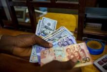 A man trades U.S. dollars for Ghanaian cedis at a currency exchange office in Accra, Ghana, June 15, 2015. PHOTO BY REUTERS/Francis Kokoroko