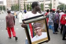 A man holds a framed portrait of Nigeria's President Muhammadu Buhari outside the venue of Buhari's inauguration in Abuja, May 29, 2015. PHOTO BY REUTERS/Akintunde Akinleye