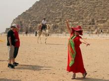 A tourist poses in front of a policeman on a camel at the pyramids plateau, Egypt, June 11, 2015. PHOTO BY REUTERS/Asmaa Waguih