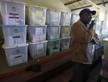 A plain clothed policeman stands in front of ballot boxes in a tallying centre at Mathare slum in Nairobi