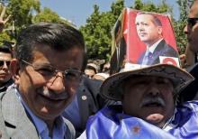 Turkish Prime Minister Ahmet Davutoglu (L) poses with a supporter of AK Party wearing a hat with a picture of President Tayyip Erdogan, as he leaves from a mosque following Friday prayers in Kahramanmaras, Turkey, June 5, 2015. PHOTO BY REUTERS/Umit Bektas