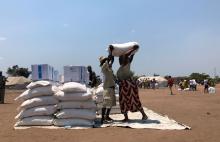 A man helps a woman lift a bag of aid during a distribution for victims of Cyclone Idai at a camp in Guara Guara, outside Beira, Mozambique, October 8, 2019. PHOTO BY REUTERS/Emma Rumney
