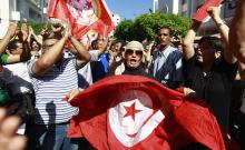 Anti-government protesters wave Tunisian flags as they rally for the dissolution of the Islamist-led government in Sfax