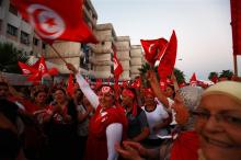 Anti-government protesters wave Tunisian national flags and shout slogans during a demonstration in Tunis