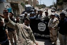 Members of the Iraqi Army's 9th Armoured Division are photographed with an Islamic State flag, claimed after fighting with Islamic State militants in western Mosul, Iraq, June 17, 2017. PHOTO BY REUTERS/Alkis Konstantinidis