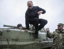 Ukrainian Prime Minister Arseny Yatseniuk jumps off an armored personnel carrier (APC) during a visit to the International Center of Peacekeeping and Security in Yavoriv, west of Lviv, October 21, 2014. PHOTO BY REUTERS/Andrew Kravchenko