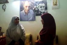 The wife, Asrar (L), and daughter, Asmaa, of Mahmoud Abdel Hadi pose for a picture beneath photographs of Hadi (top L) and his son Assem at the family home in the Nile Delta city of Mansoura, Egypt, July 28, 2015. PHOTO BY REUTERS/Asmaa Waguih