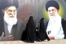 Iraqi women walk past a poster depicting images of Shi'ite Iran's Supreme Leader Ayatollah Ali Khamenei at al-Firdous Square in Baghdad, February 12, 2014. PHOTO BY REUTERS/Ahmed Saad